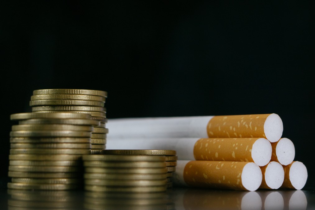 Pièces de monnaie empilées à côté de cigarettes illustrant les économies liées au prix tabac espagne.